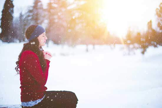 A woman kneeling in the snow and praying as she seeks spiritual growth