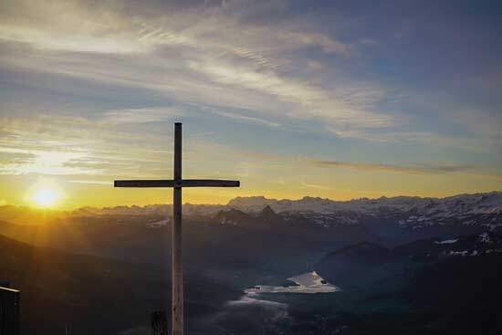 Cross of Jesus, during sunrise shining over the landscape, reminding us of Romans 5:8- God loved us while we were yet sinners