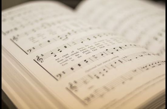 Open Adventist hymnal book, showing song lyrics and music.