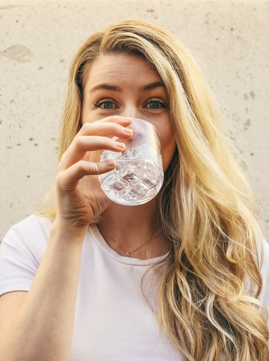 A woman hydrating by drinking clean water.
