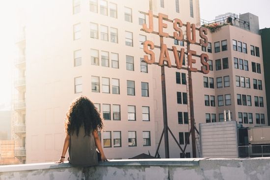 A girl sitting and looking at a sign that says Jesus Saves