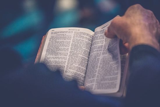 A hand turning the pages of a Bible