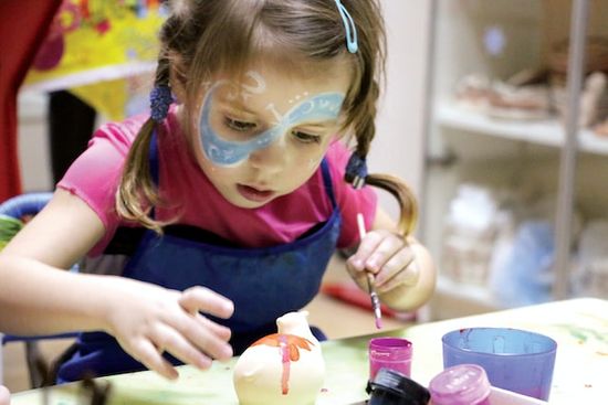 A little girl painting a small sculpture at a vacation Bible school