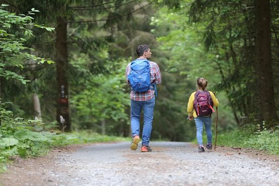 A camp counselor and camper walking on a forest path