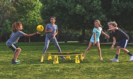 Children playing a game of spike ball on the grass at a Christian camp