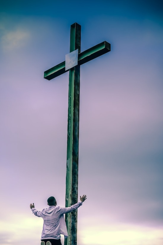 A man kneeling before a Cross and praying to Jesus in repentance