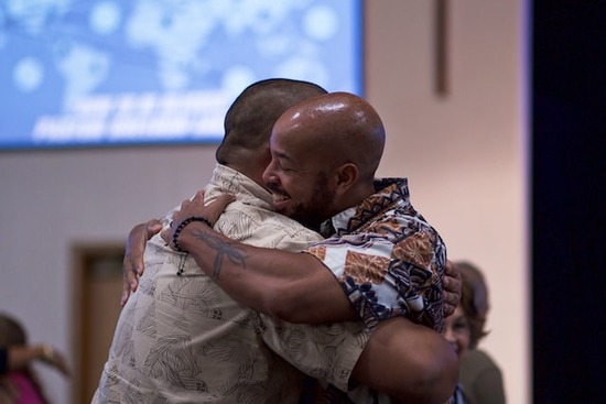 Two men hugging together as they reconcile in their friendship by apologizing and forgiving each other through Holy Spirit.