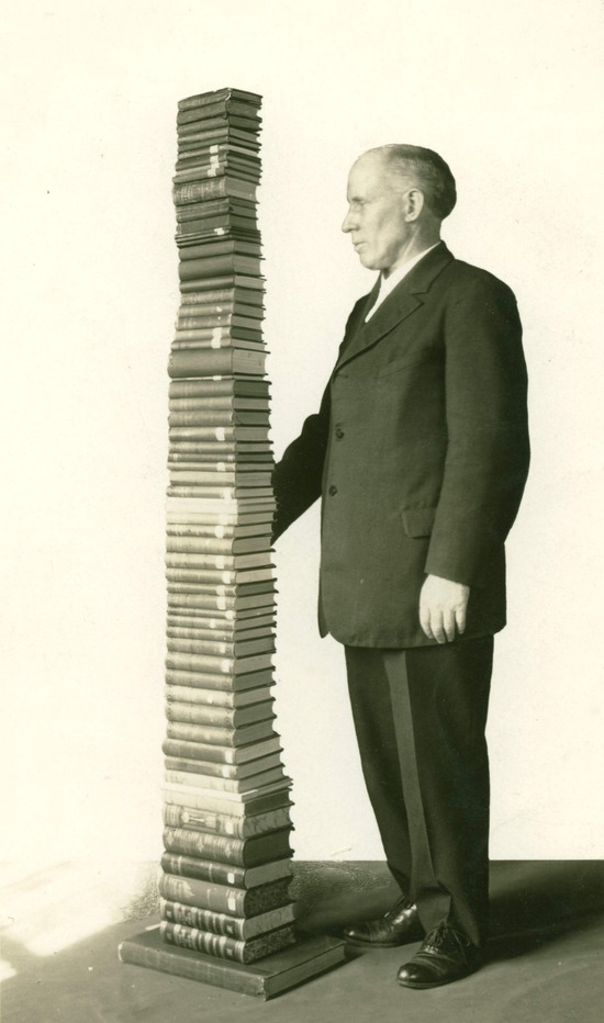  A man standing next to a stack of Ellen White's books