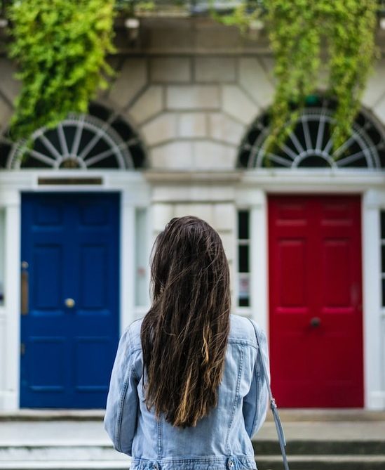 A woman standing before a blue door and a red door, exercising God's gift to human beings of freedom of choice