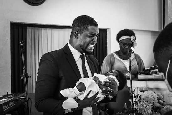 An Adventist pastor holding a baby during a baby dedication ceremony