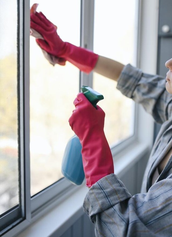 A woman washing windows to make her home a clean and restful environment