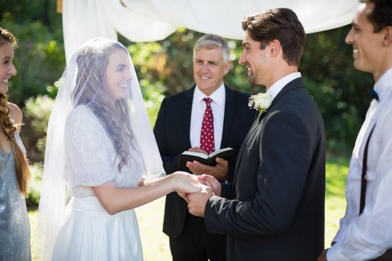 A couple standing before a minister and holding hands during their wedding ceremony