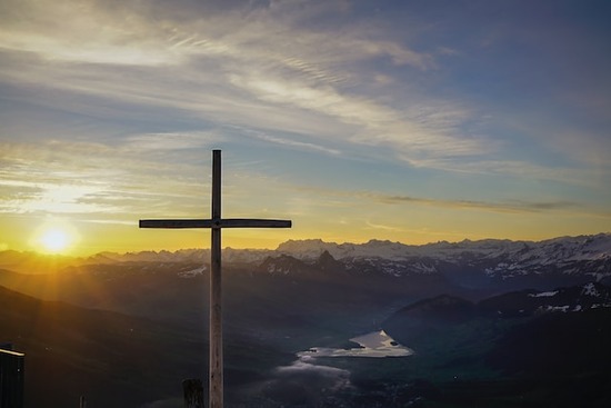 A cross illuminated by a sunset symbolizing faith in Jesus