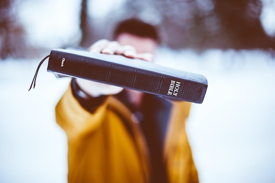 A man holds a Bible out