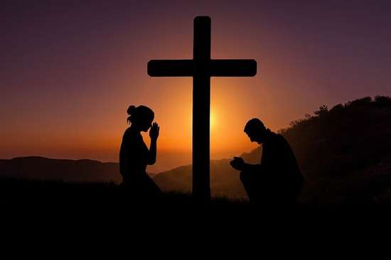  A woman and man kneeling at the cross asking God to be faithful