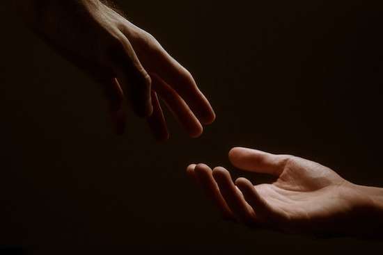 A hand reaching out to hold onto another hand