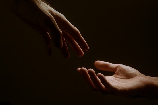 A hand reaching out in love to grab another hand
