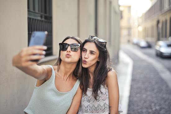 Two young women pursing their lips and posing for a selfie showing self love