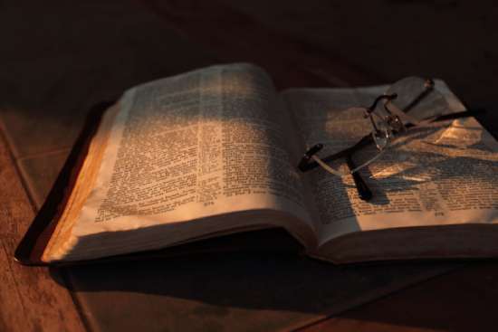 A pair of glasses on top of an open Bible