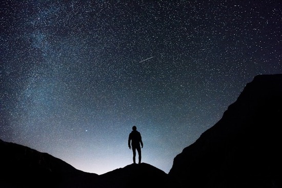 A man on a mountain under a sky full of stars
