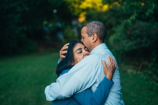 An older couple wraps their arms around each other in a loving embrace.