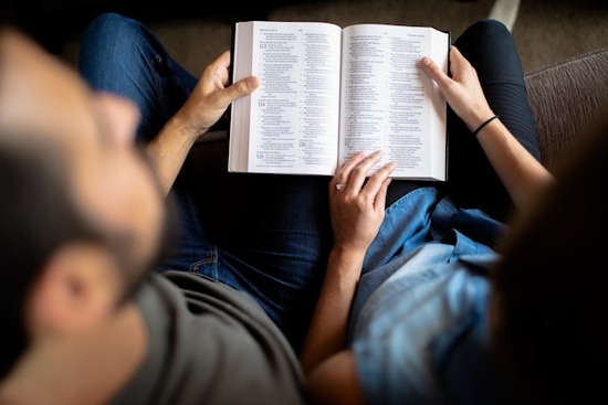 A couple holds an open Bible so they can read the Word of God together.