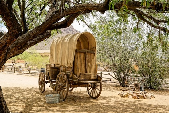 A covered wagon sits in preparation for a long journey.