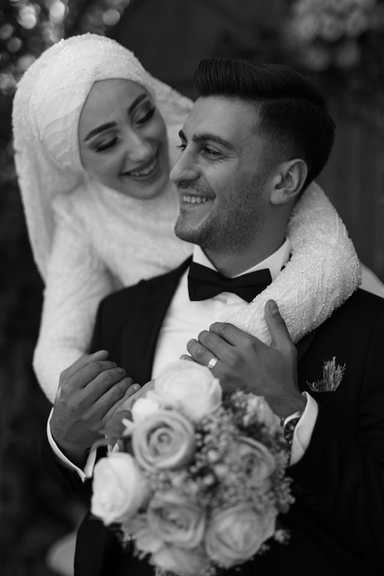 A Muslim woman in white wedding attire with her arms around her husband, representing an interfaith marriage
