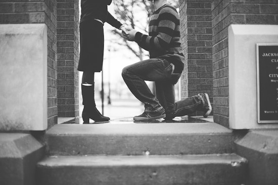 A man gets on one knee to propose to his girlfriend.