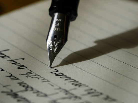 A fountain pen writes on a piece of lined paper.