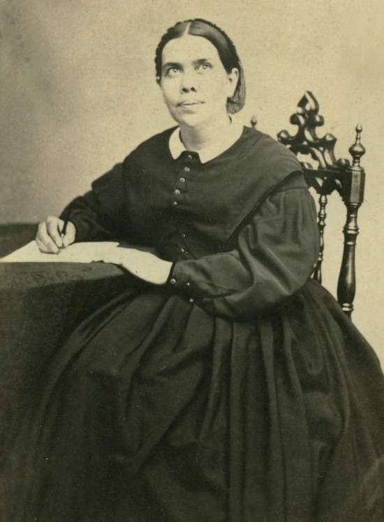A black-and-white photograph of Ellen White writing at a table.