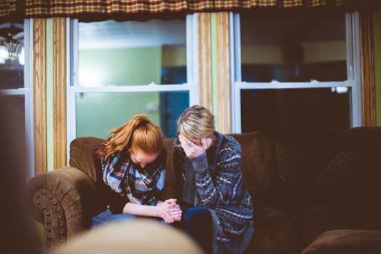 Two women bow their heads in prayer as they seek the Lord's guidance.