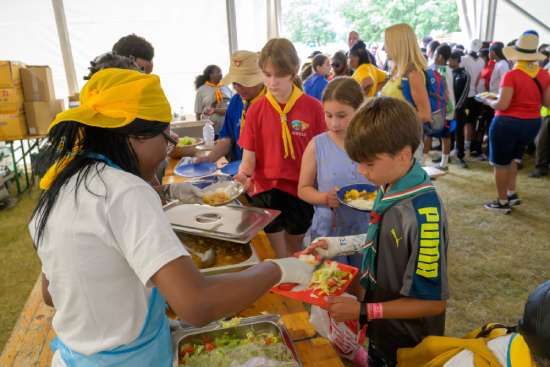A line of volunteers serving a meal to Pathfinders