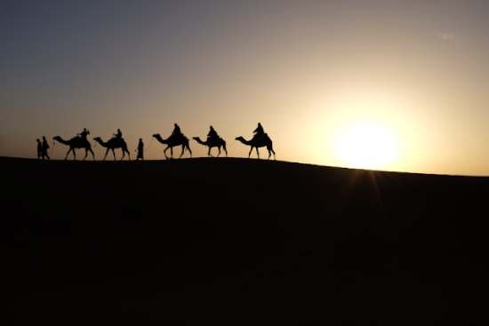 A group of men ride camels across the desert, representing the journey the Wise Men took through the desert to see Jesus.