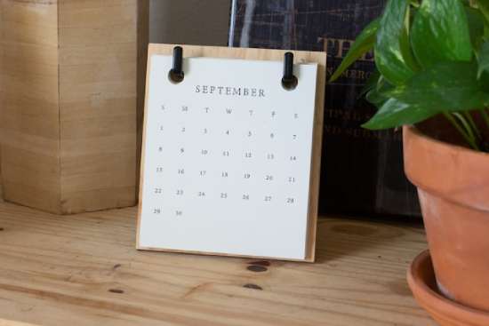 A calendar for the month of September resting on a wooden desk.