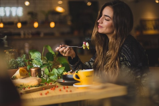 A woman smiles as she prepares to take a bite of her vegetarian pasta salad.