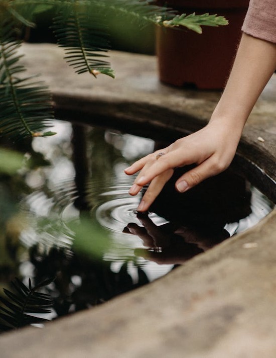 A woman touching a finger to a pool of still water